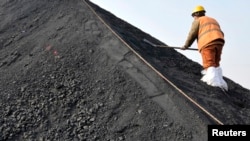 一名中国工人在山东日照港铲着从澳大利亚进口的煤炭。（资料照片）