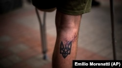 資料照 - 照片上一名烏克蘭亞速營傷員受傷的小腿上紋著亞速營標誌的刺青。照片攝於2022年5月5日，這位傷員拄著拐杖去基輔一家醫院參加康復鍛煉。