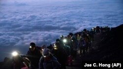 资料照：一群游客凌晨攀登日本富士山观看日出美景。（2019年8月27日）