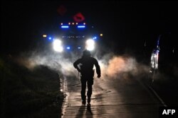 Law enforcement officers are seen outside the home of suspect Robert Card's father and brother in Bowdoin, Maine on Oct. 26, 2023, in the aftermath of a mass shootings in Lewiston, Maine.