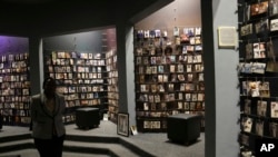 A tourists walks past family photographs of some of those who died in an exhibition at the Kigali Genocide Memorial center in Kigali, Rwanda, April 4, 2024. 
