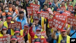 Taiwanese workers hold slogans reading 'Congress Amended the Law to Support Workers' Rights' and 'The Regime Has No Honeymoon'' during a May Day rally in Taipei, Taiwan, May 1, 2024. 