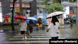 ພວກຄົນທີ່ກຳລັງຍ່າງ ຢູ່ທາງເສັ້ນນຶ່ງ ໃນລະຫວ່າງພາຍຸຝົນຢູ່ໃນເຂດເສິນເຈິ້ນ ຂອງແຂວງກວາງດົງ ຂອງຈີນ, ວັນທີ 21 ເມສາ 2024 (cnsphoto via Reuters)