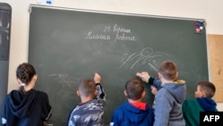 ພວກເດັກນ້ອຍນັກຮຽນຢູເຄຣນ ກຳລັງຂຽນຊື່ເຂົາເຈົ້າໃສ່ກະດານ ໃນ້ຫ້ອງຮຽນທີ່ໂຮງຮຽນປະຖົມ Jules Ferry ໃນເມືອງ Tomblaine ມັນທີ 25 ກັນຍາ 2023