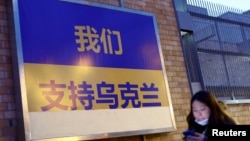 一名女子走過加拿大駐北京使館外面掛出的支持烏克蘭的標語牌（2022年3月2日）