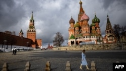 ແມ່​ຍິງ​ຄົນ​ນຶ່ງ​ຍ່າງ​ໃກ້​ວັງ​ເຄ​ຣັມ​ລິນ ແລະ ໂບດວິ​ຫານ ເຊັ້ນ ບາ​ຊິ​ລ​ສ໌, ໃຈ​ກາງ​ນະ​ຄອນຫຼວງ ມົ​ສ​ກູ, ຣັດ​ເຊຍ, 22 ກຸມ​ພາ 2022. 