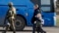 Жители Мариуполя, покинувшие убежище на металлургическом комбинате «Азовсталь», идут к автобусу в сопровождении военнослужащего российской армии (AP)