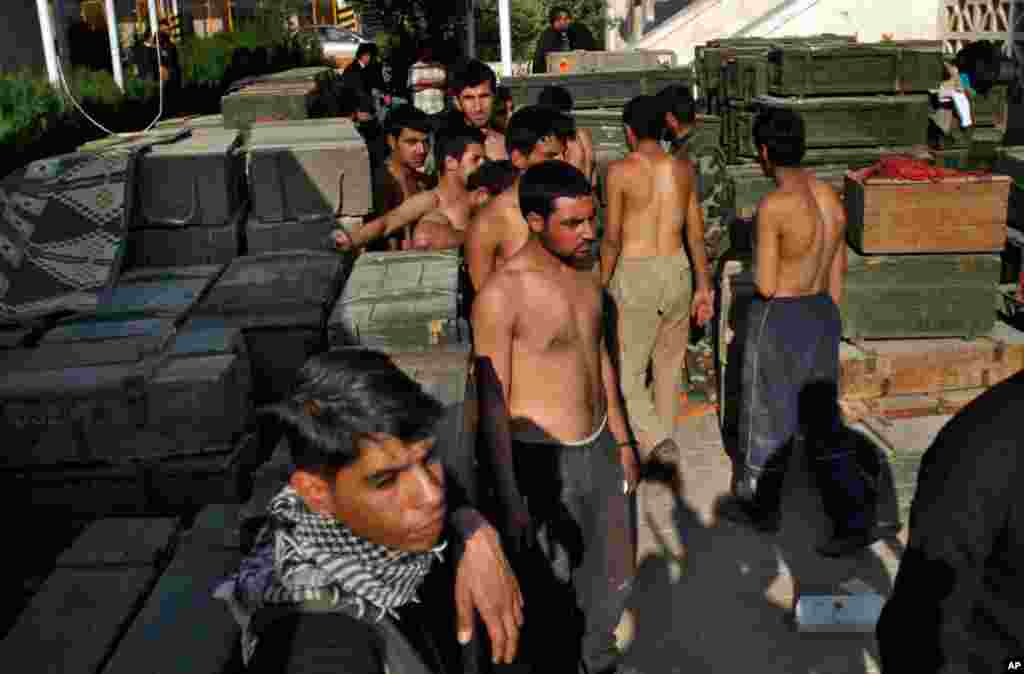 Syrian army soldier prisoners stand near ammunition after Syrian fighters took over the military base in Aleppo, November 19, 2012. 