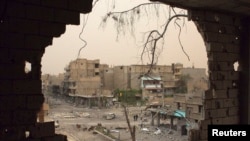 从叙利亚代尔祖尔被炸毁的房屋窟窿内可见人们在街上行走