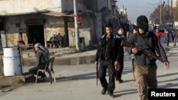 自由叙利亚军战士在阿勒颇一处居民区的街头巡逻盘查，防止与基地组织有关联的“伊拉克与大叙利亚伊斯兰国”组织成员混入。（2014年1月7日）
