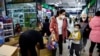 FILE - A woman and a child walk past workers sorting toys at a shopping mall in Beijing, Jan. 11, 2023. 