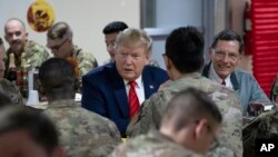 2019年11月28日星期四，特朗普總統在共和黨參議員約翰·巴拉索陪同下共進晚餐時微笑。他在當天的感恩節突防阿富汗巴格拉姆空軍基地。 （美聯社照片）