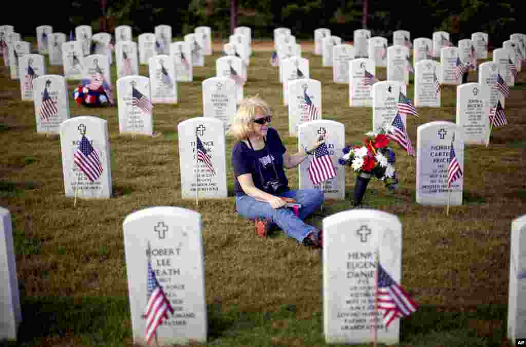 Cathy Ridge touches an American flag at the grave of her husband, retired U.S. Marine Gunnery Sgt. Charles Edward Ridge, May 28, 2012, at the Georgia National Cemetery in Canton.