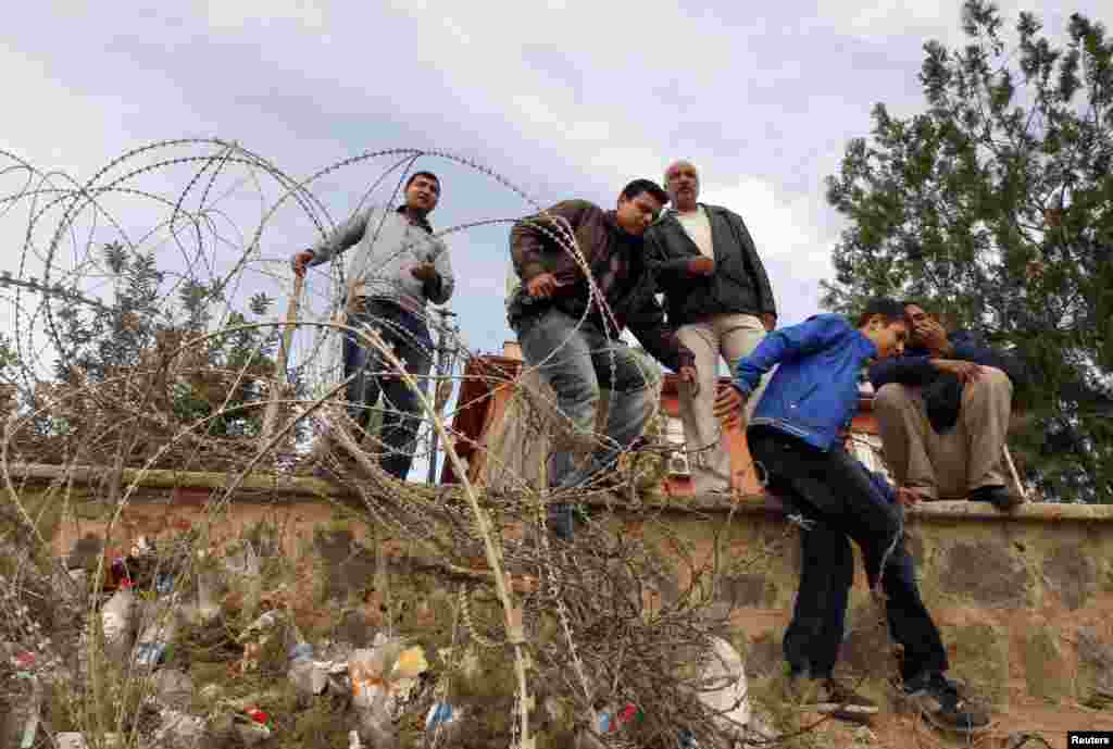Syrian refugees try to cross the border fence from the northern Syrian town of Ras al-Ain into Turkey during an air strike on Ras al-Ain, in the Turkish border town of Ceylanpinar, Sanliurfa province, Turkey, November 13, 2012. 