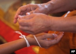 A Buddhist monk ties a holy thread to a member of Wild Boars soccer team for good luck after marking the completion of their serving as novice Buddhist monks. The boys served as novice monks to give thanks for their survival and to show their gratitude to all those who helped them.