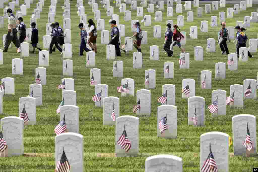 美国男女童子军2018年5月26日帮助在洛杉矶国家公墓放置旗帜后，在墓碑之间漫步。童子军在阵亡将士纪念日前的仪式中将美国国旗放在了退伍军人的墓碑前。超过6000名儿童参加了此次活动。每名穿制服的儿童在每个坟墓的地面放置一面旗帜并敬礼 组织者说，他们插上了将近9万面小旗帜以表示敬意。