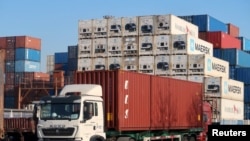 2019 年 12 月 12 日，中国天津，一名工人在天津港附近的物流中心驾驶一辆载有集装箱的卡车。（路透社照片）