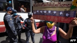 Una mujer sostiene un cartel que dice “Justicia para todas las mujeres” mientras agentes de policía custodian una manifestación por el Día Internacional para la Eliminación de la Violencia contra la Mujer en Caracas, Venezuela, el 25 de noviembre de 2020.