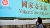香港一名妇女走过街头的国安法宣传牌。（2020年6月30日）