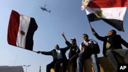 1月25日部分埃及民众在解放广场向天空飞过的军用直升机挥舞国旗