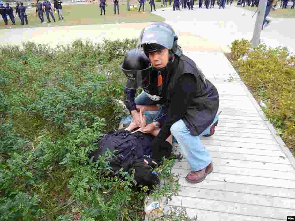 兩名穿上防暴裝備的警員將一名示威者制服按在地上，並以索帶縳上雙手拘捕