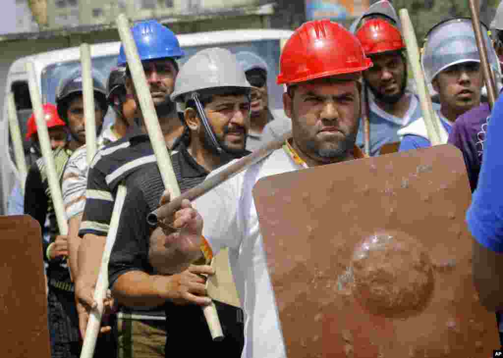 2013年7月2日，埃及伊斯兰主义总统穆尔西的支持者顶盔贯甲手持棍棒在开罗总统府附近的拉比亚&middot;阿达维亚清真寺广场操练队伍。