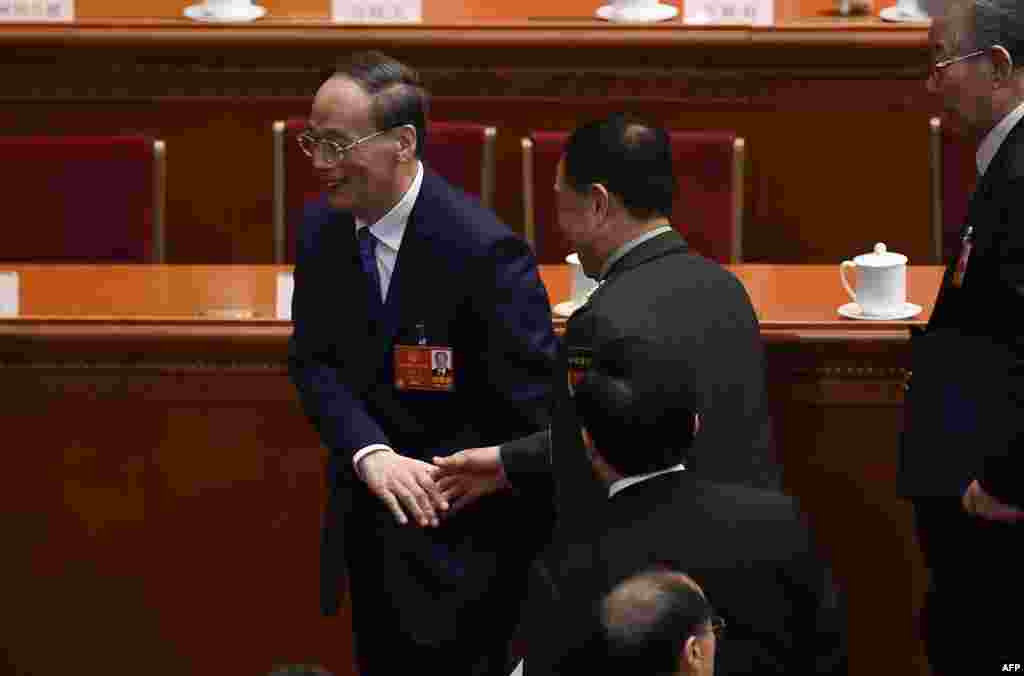 2018年3月5日，人大代表王岐山（左）在人大开幕式之后离开时与一位军方代表代表握手。这位上将佩戴中央军委的臂章，范长龙过去多次佩戴这个臂章。