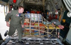 U.S. Coast Guard Petty Officers Nicholas Eudier, left, and Nate Matthews unload relief supplies for Hurricane Dorian victims from their C-130 aircraft in Andros, Bahamas, Sept. 7, 2019.