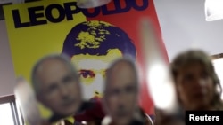 委内瑞拉反对派政党联盟总部在卡拉卡斯召开的一个记者会上，人们在印有反对派领导人洛佩斯画像的墙壁前，手举反对派领导人莱德斯马的画像。（2017年8月1日）