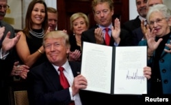 President Donald Trump smiles after signing an executive order to make it easier for Americans to buy bare-bone health insurance plans and circumvent Obamacare rules, at the White House in Washington, Oct. 12, 2017.