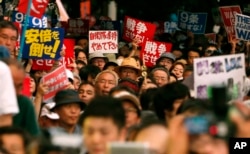 日本国会通过扩充军事力量的防卫法案后，抗议者在国会大厦前举行反战示威集会。