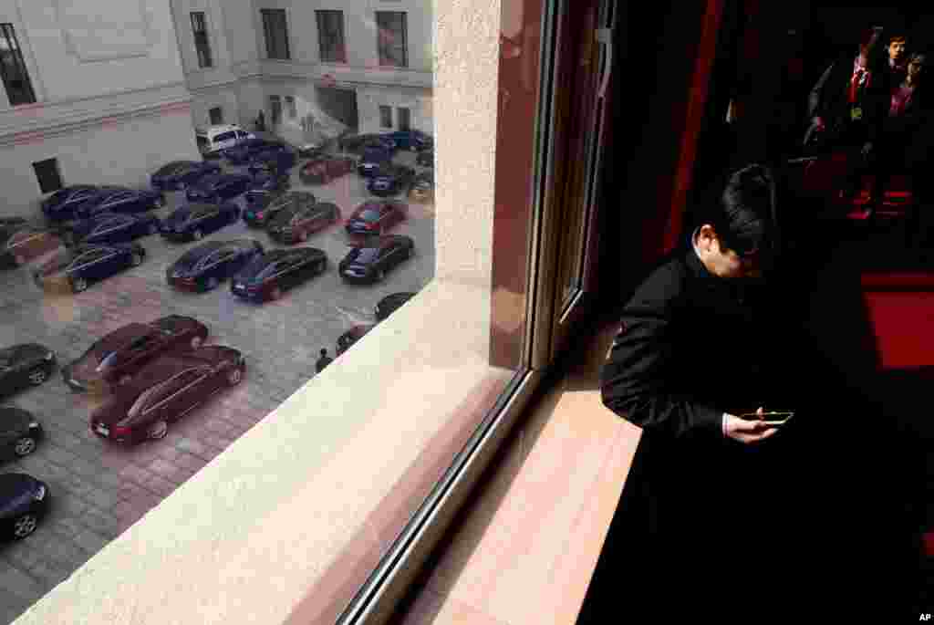 2013年3月5日中国在北京举行第十二届人大开幕式之后，当政府官员的车辆准备离开人民大会堂的时候，一名人大代表查看他的手机。