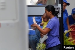 2014年7月14日洪都拉斯北部圣佩德罗苏拉国际机场，一名妇女和她的儿子进入一辆载有从美国遣返回国者的汽车前往车站。