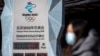 2022年1月15日，2022年北京冬季奥运会开幕前，一名戴着口罩的妇女走过倒计时钟（美联社）。
