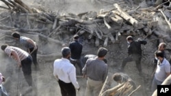 伊朗民眾星期天在伊朗西北部一個被地震摧毀的村莊搜尋有用的物品