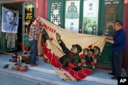 北京旧货市场上的1969年的文革横幅画布，上面有戴红卫兵袖章的毛泽东、其他文革领导人林彪、江青和周恩来以及红卫兵。横幅上写着“大海航行靠舵手” 和“毛主席检阅文化革命大军”（2016年5月16日）