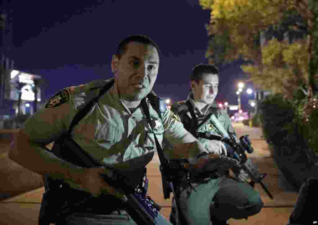 Police officers advise people to take cover near the scene of a shooting near the Mandalay Bay resort and casino on the Las Vegas Strip, Sunday, Oct. 1, 2017, in Las Vegas.