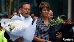 12月16日，澳大利亞總理阿博特伉儷在悉尼發生劫持人質事件現場敬獻鮮花。