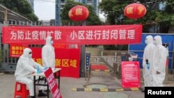 身穿防护服的工作人员在武汉一个住宅小区的入口设立登记与体温测量的检查点。（2020年2月13日）