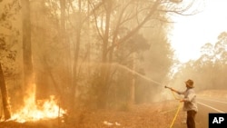 澳大利亚新南威尔士州莫鲁亚镇附近一名男子正在用水龙带灭火（2020年1月4日）。