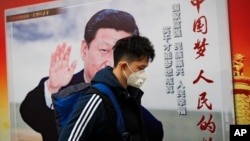 北京街道上，戴口罩的行人走過帶有中國領導人習近平像的海報，海報上有標語“中國夢人民的夢”（2017年10月26日）