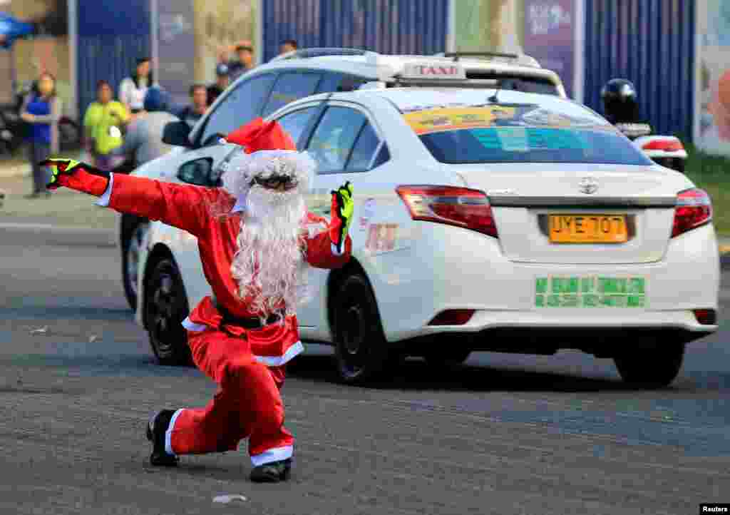 在菲律宾马尼拉的帕赛（Pasay）市，51岁的交通警察Ramiro Hinojas穿着圣诞老人的服装，在一个十字路口指挥司机行驶。（2017年11月28日）