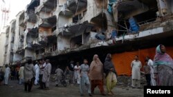 巴基斯坦最大城市卡拉奇3月4 日在一座清真寺外發生汽車炸彈事件﹐附近居民在一座損毀得建築物前視察情況。