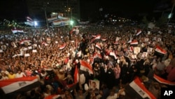 被推翻的埃及总统穆尔西的支持者在开罗纳塞尔城开斋祈祷后的示威活动中手持穆尔西肖像，挥舞埃及国旗，并呼喊口号。