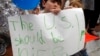 Shua Rich, age 6, holds his sign as he protests with his mother during a rally against U.S. immigration policies outside an office for Rep. Kevin Yoder, June 22, 2018, in Overland Park, Kan.