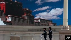 警察在天安门广场巡逻，巨型屏幕上显示着西藏的蓝天白云。（资料照片）