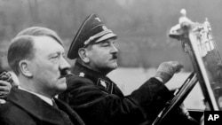 在这张日期不明的照片中，希特勒坐在纳粹党的梅赛德斯-奔驰轿车内，开车者为他的亲信、1936年病死的尤利乌斯·施雷克。（历史资料照片）