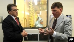 FILE - Tom Geisbert, right, a professor of Microbiology and Immunology at the University of Texas Medical Branch, explains to Texas Gov. Rick Perry the work researchers are conducting in a Bio Safety Level 4 lab in the Galveston National Laboratory, Oct.