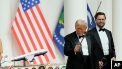 Президент Дональд Трамп держит саблю после разрезания ею торта на балу главнокомандующего. За спиной Трампа стоил вице-президент Дж. Д. Вэнс. 20 января 2025 года, Вашингтон