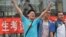 A student pose for a photo after taking the 2014 college entrance exam of China, or the "gaokao", outside a high school in Beijing, June 8, 2014.. 